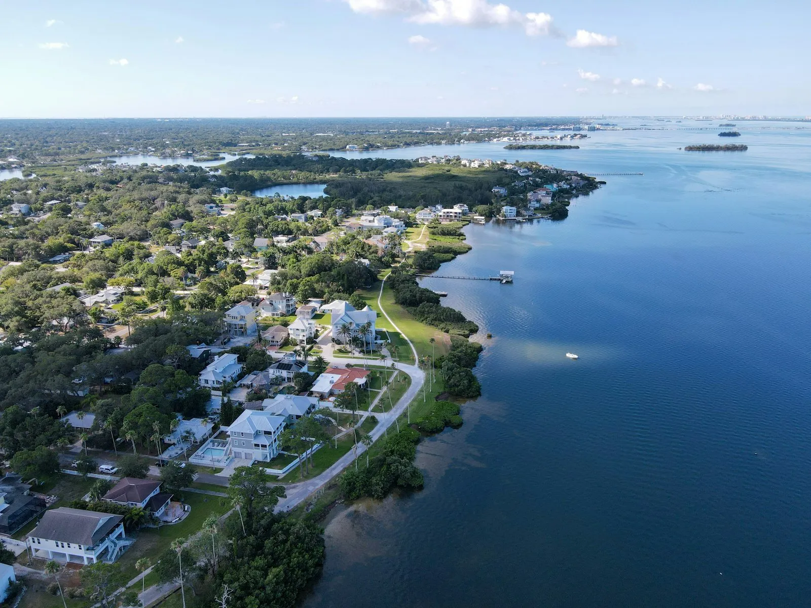 A shoreline neighborhood with mangroves and tree-lined streets along the bay, seen from the air